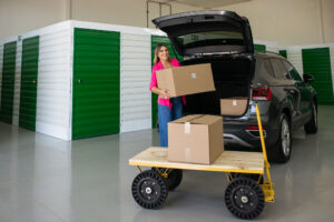 uma mulher de blazer rosa segurando uma caixa em um self storage